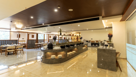 hotel dining area with a central buffet counter and seating area at Essentia Resort & Spa, Sirsi 