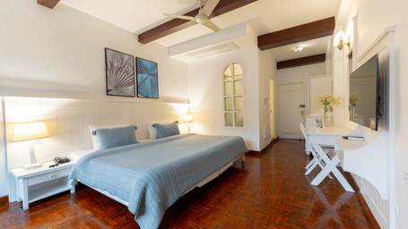 A full view of a deluxe suite showing the bed, seating area, work desk, and wall-mounted television - Johnson Lodge & Spa, Manali