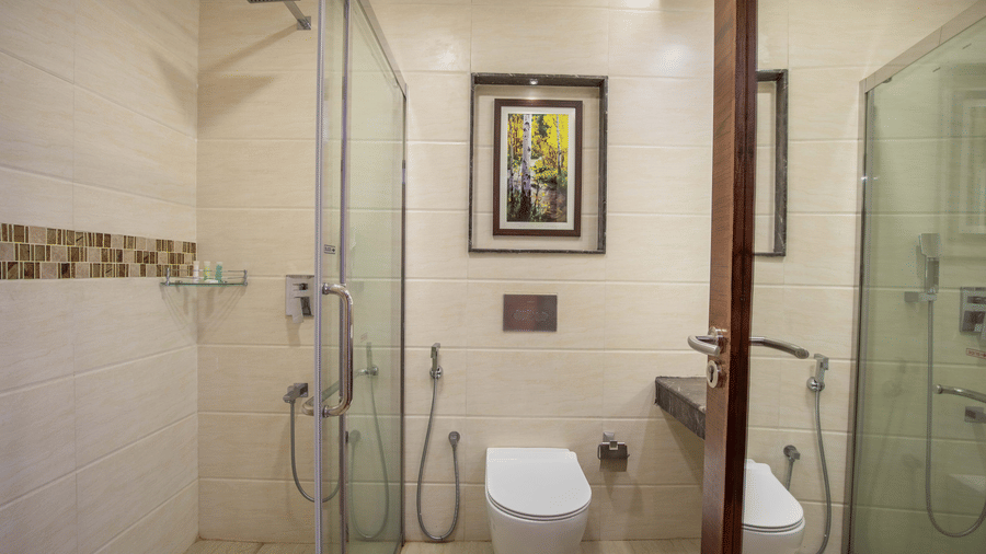 Washroom of Premium Twin Room at Avana Resort featuring a western toilet, tiled walls, and a glass walk-in shower.