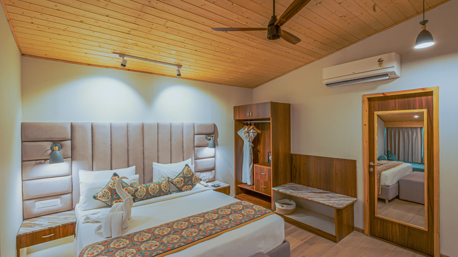 A view of a bedroom showing the large bed, bedside tables, and mirrored wardrobe at Bamboo Saa Resort & Spa, Udaipur.