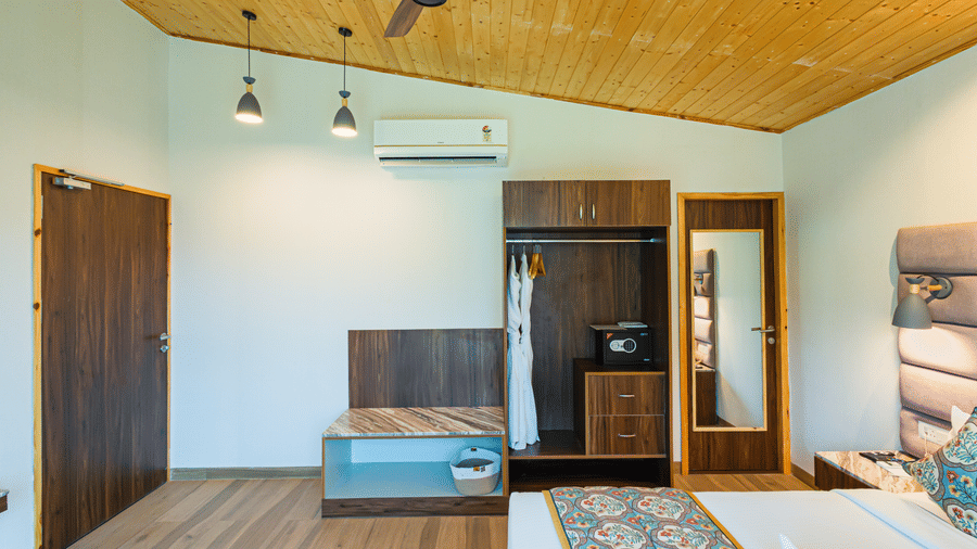 A view inside a room showing the wardrobe, safe, luggage shelf, and air conditioning unit at Bamboo Saa Resort & Spa, Udaipur.