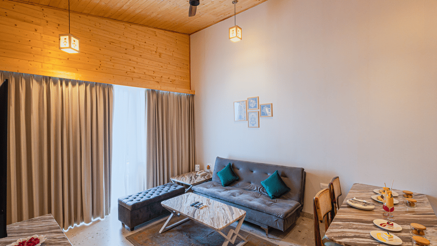 Sajjan Villa at Bamboo Saa Resorts and Spa, Udaipur featuring a seating area with sofa, chairs, and centre table and a dining space.