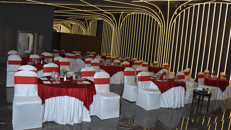 A banquet hall at Comfort Inn Sapphire by Eastlynn Collections, Jaipur with arranged tables, chairs, and patterned wall design.