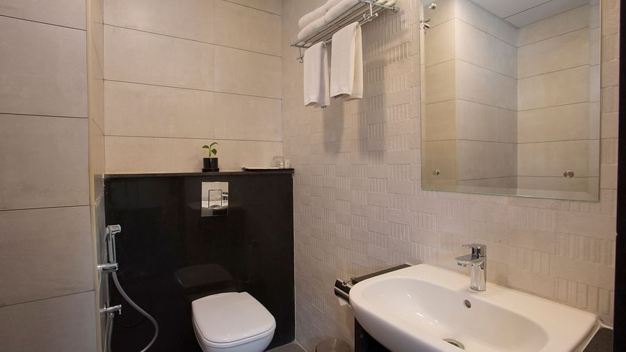 A modern bathroom with beige tiles, a wall-mounted toilet, basin and a mirrored cabinet - De Venetian by TGI, Brookefield