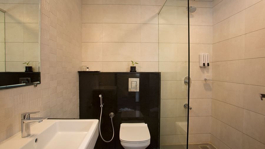 A clean and contemporary hotel bathroom with a glass shower enclosure and black accent wall - De Venetian by TGI, Brookefield