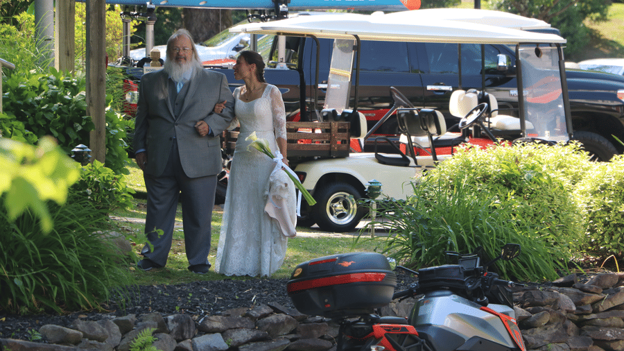 a father along with his daughter dressing in a white wedding gown and a golf cart behind them - Historic Tapoco Lodge