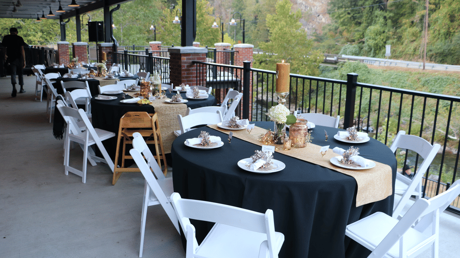 a dining area with well arranged tables having plates and flowers overlooking a beautiful lawn - Historic Tapoco Lodge