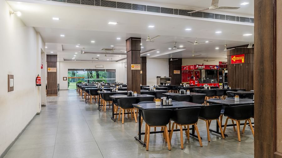 Dining tables with various seating capacities, ample lighting and eatery stalls located inside the restaurant of Hotel Highway King, Behror.