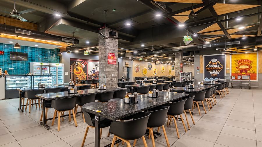 Wide-angle view of the dining space with black chairs and modern lighting at Hotel Highway King, Bilaspur.