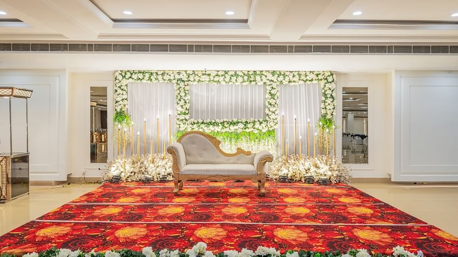 Indoor wedding stage setup with floral arrangements and red carpet at Hotel Highway King, Bilaspur.