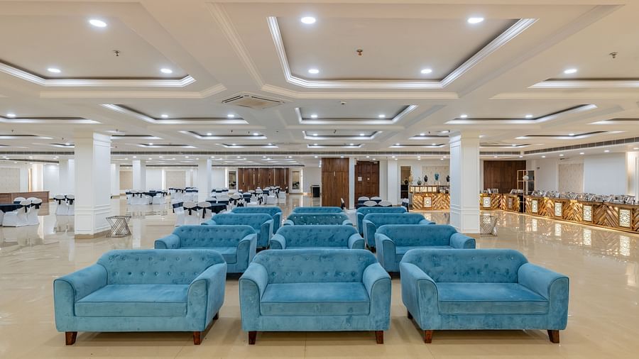Well-organised hall with stylish ceiling design and blue sofas at Hotel Highway King, Bilaspur.