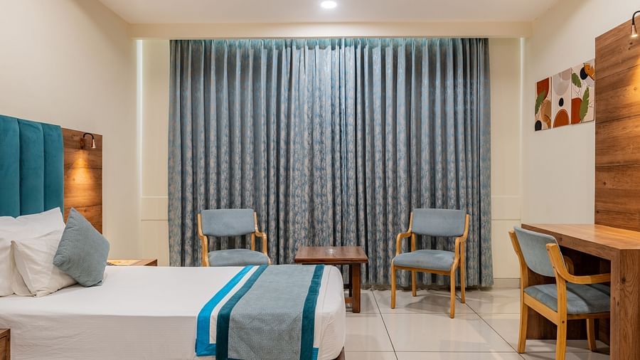KIng Twin Bed Room with curtain-lined windows and coordinated seating area at Hotel Highway King, Bilaspur.