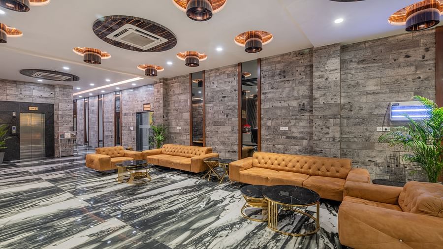 Modern hotel lobby with stylish ceiling lights, stone walls, and leather sofas at Hotel Highway King, Bilaspur.