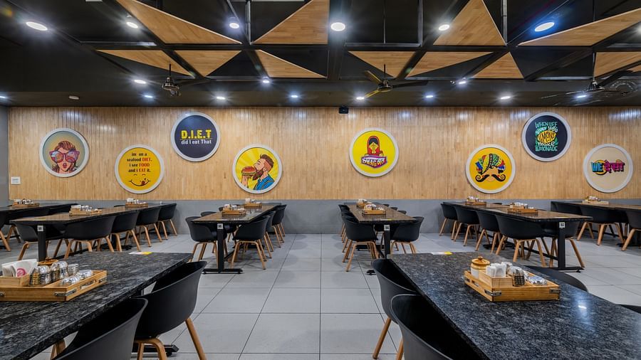 Colourful food-themed wall decor and neatly arranged tables at Hotel Highway King, Bilaspur.