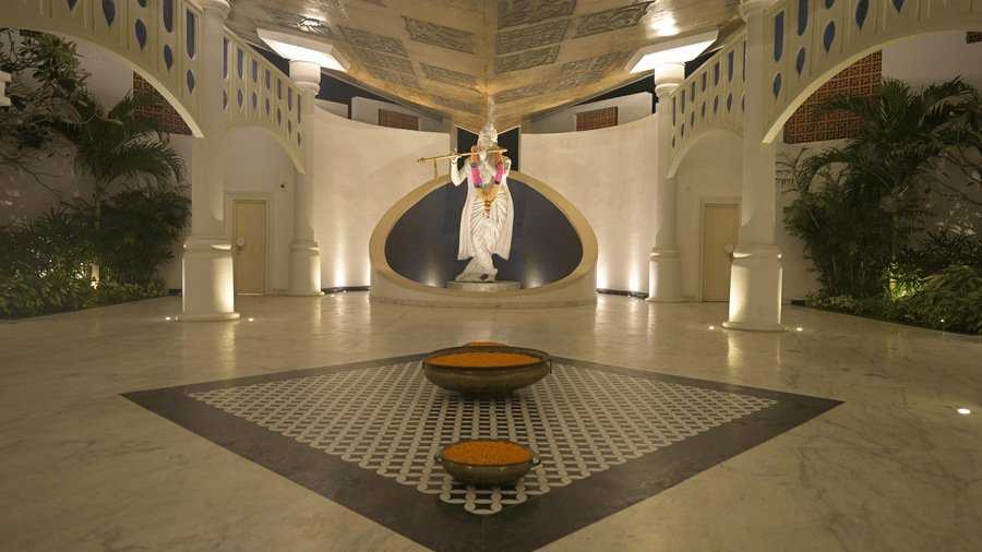 A large indoor hall with a chequered floor pattern and arched entryways at Hotel Sonar Bangla, Mayapur.