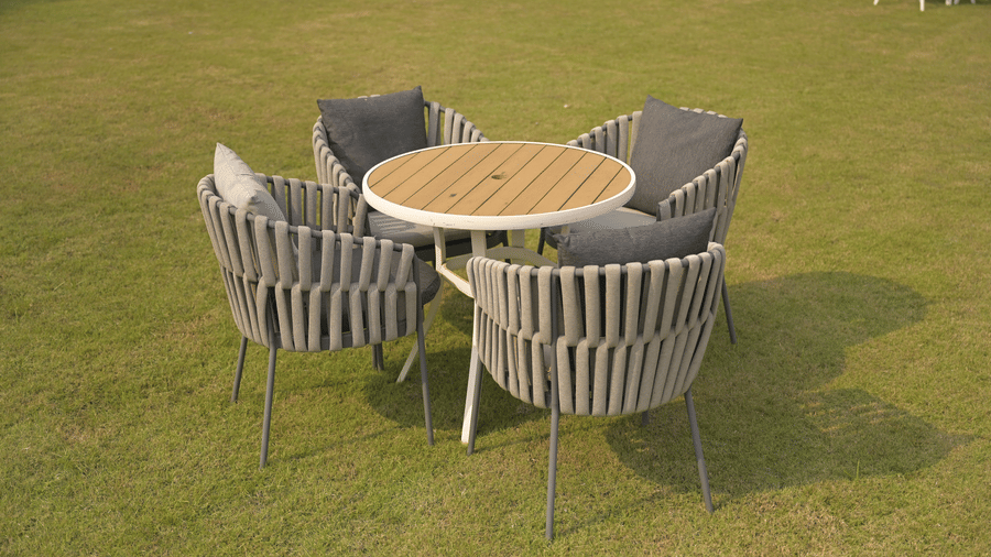 Round wooden outdoor table with grey chairs arranged neatly on a spacious lawn at Hotel Sonar Bangla, Mayapur.