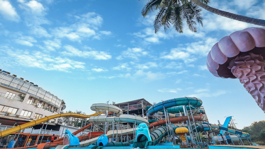 Panoramic view of the water park complex showing themed water features and structures under an expansive blue sky at Kumar Resort by Turtle.