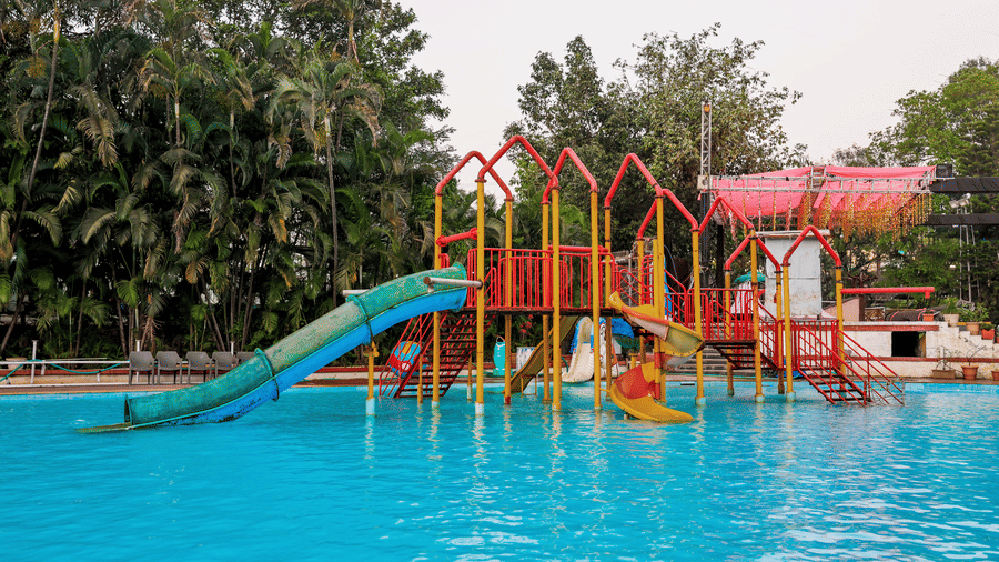 Section of the water park pool showing a simpler, multi-lane open slide and tropical landscaping at Kumar Resort by Turtle.