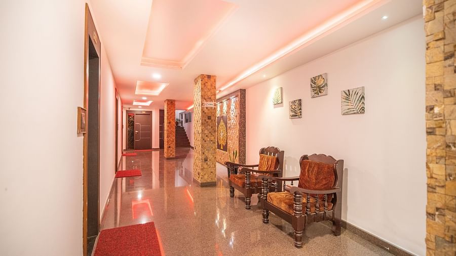 A hallway with two wooden chairs at the side at Parampara Residency, Kushalnagar.