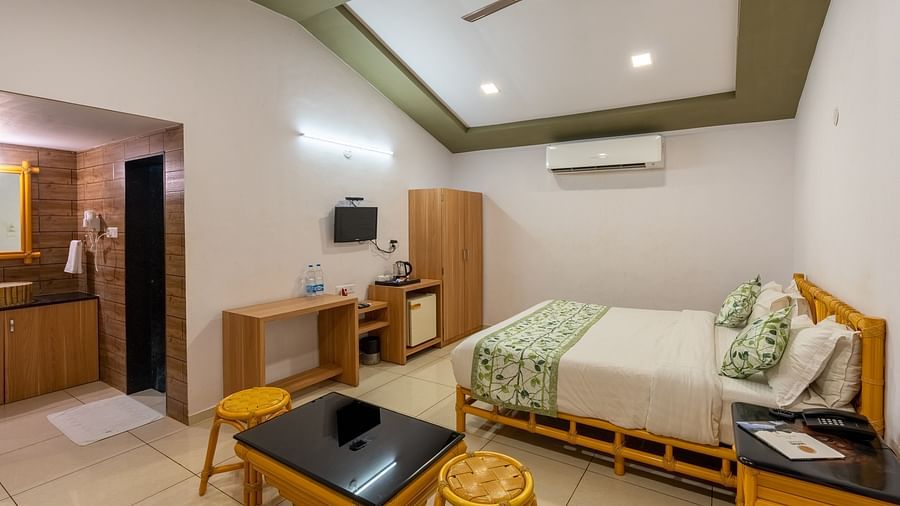 A room with a double bed, seating arrangement and work desk and chair