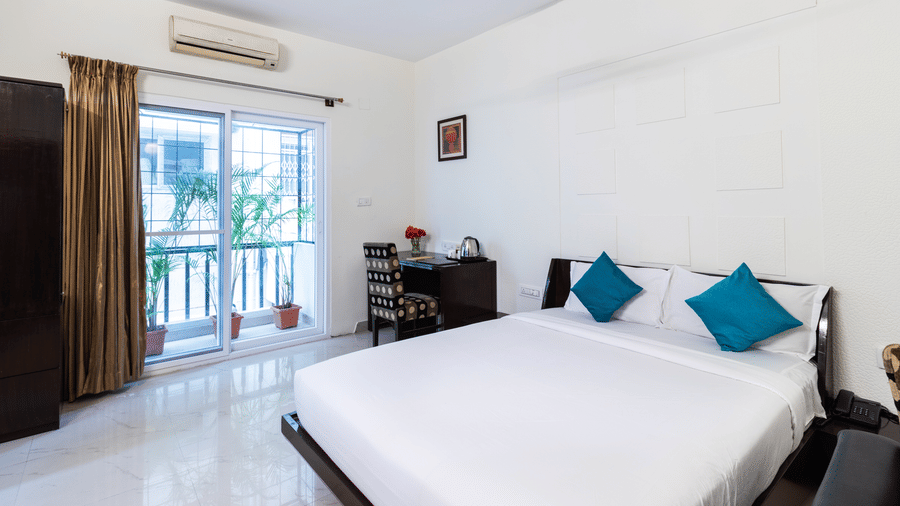 Bright guest room with double bed and private balcony at Sanctum Suites Domlur Bangalore
