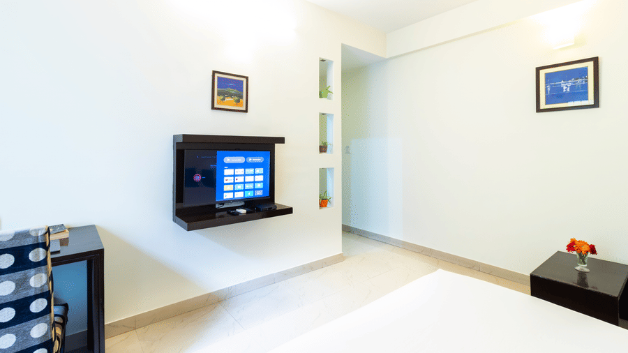 Guest room corner with TV unit and wall-mounted screen at Sanctum Suites Domlur Bangalore