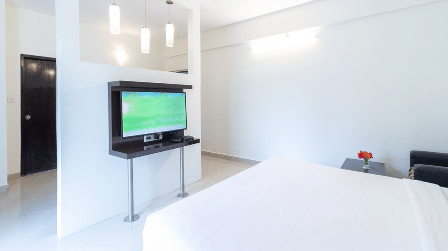 Well-furnished guest room with flat screen TV and large bed at Sanctum Suites Domlur Bangalore