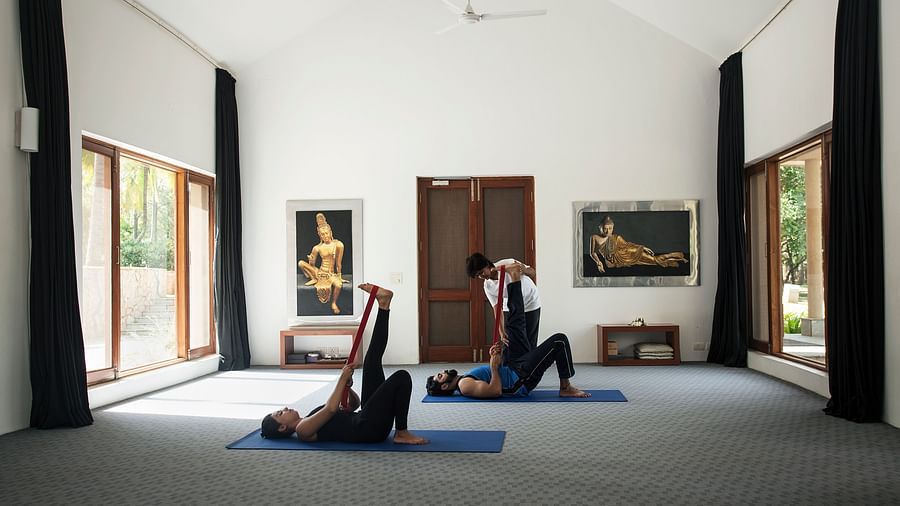 Bright room with high ceilings, person stretching on yoga mat, art on wall, minimalist interior design - Shreyas Retreat