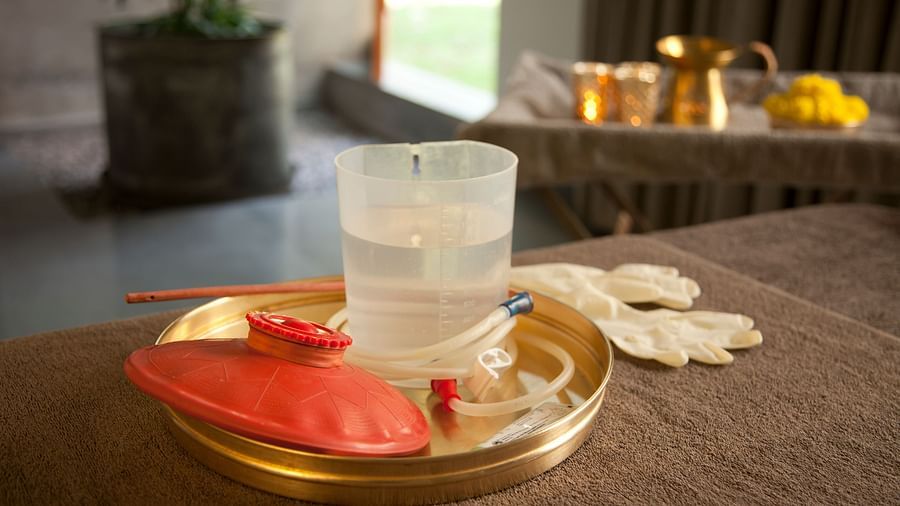 Gold tray with water glass, red flowers, white cloth, and small bowl on wooden table - Shreyas Retreat