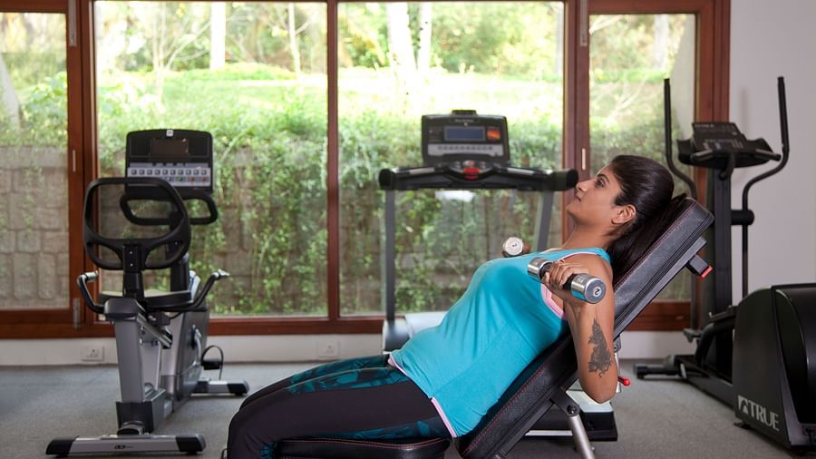 Person using exercise equipment in a room with large windows, fitness setting - Shreyas Retreat