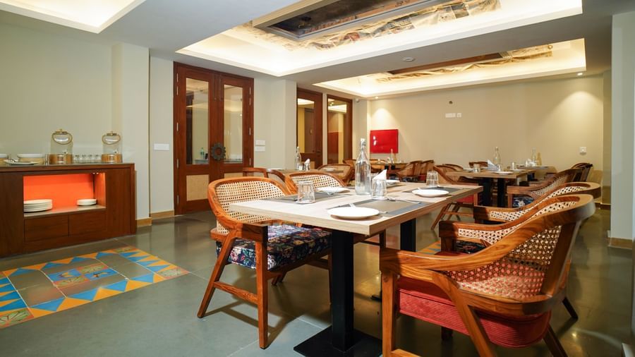 A dining room with several tables and chairs, a fireplace, and a large window | Sukama Resort & Spa, Nainital