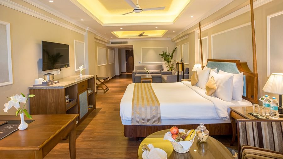 Spacious bed with a wall-mounted TV opposite it and a large window covered by curtains.