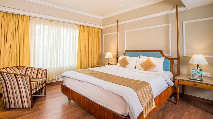 Spacious bed and a large window covered by curtains.