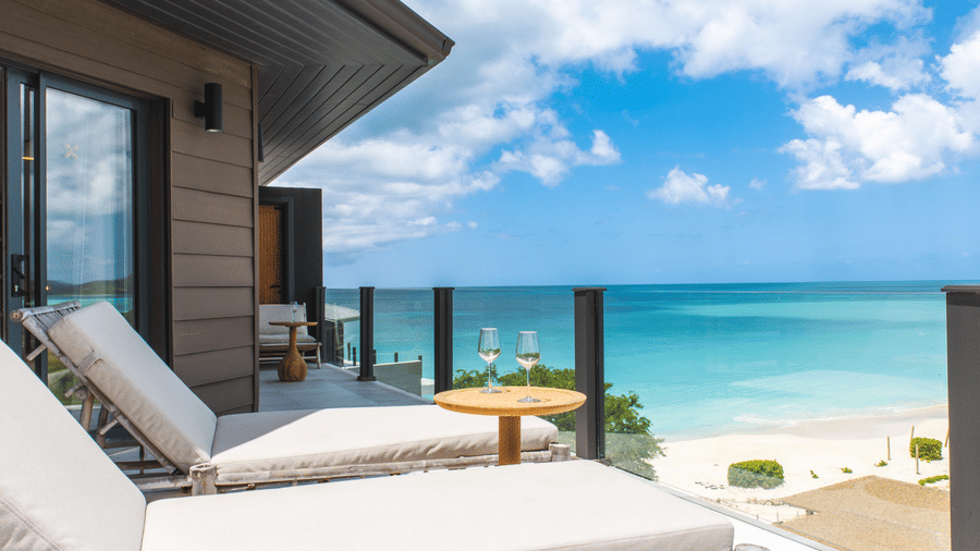 A balcony with two lounge chairs and a beach view at the Tamarind Hills Resort and Villas, Antigua.