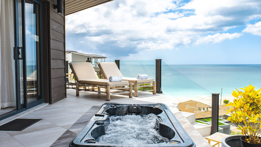 A balcony with a hot tub, lounge chairs with an ocean view at the Tamarind Hills Resort and Villas, Antigua.