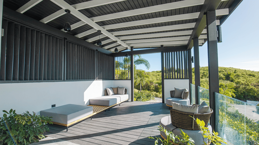 A covered outdoor deck with seating and greenery at Tamarind Hills Resort and Villas, Antigua.