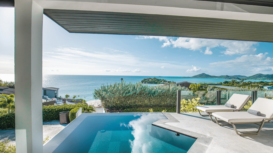 A poolside area with lounge chairs and a view of the ocean at Tamarind Hills Resort and Villas, Antigua.