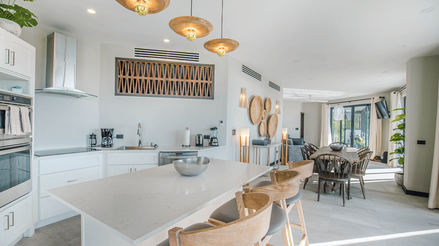 A kitchen and dining room with a kitchen island, a dining table, chairs and hanging lights at Tamarind Hills Resort and Villas, Antigua.