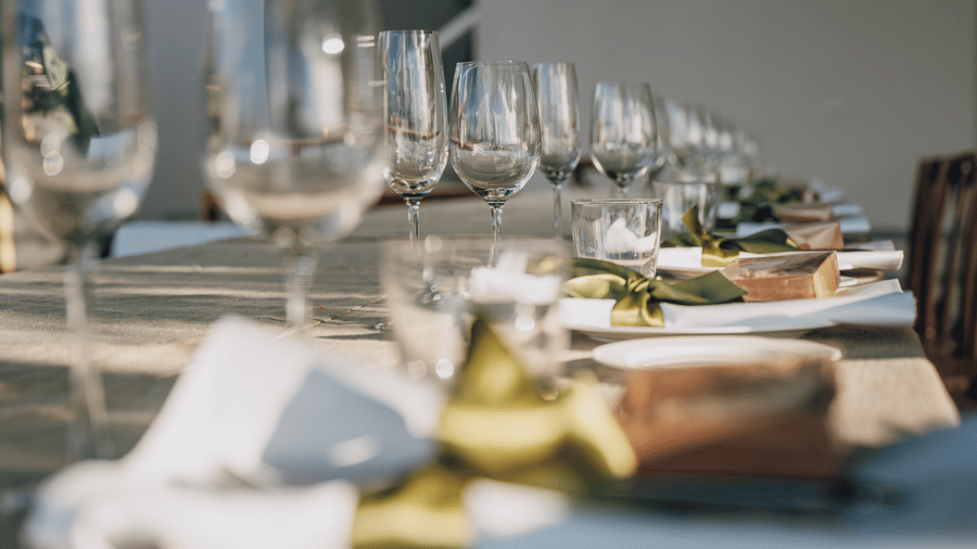 A dining table setup with wine glasses, plates, and folded napkins at Tamarind Hills Resort and Villas, Antigua.