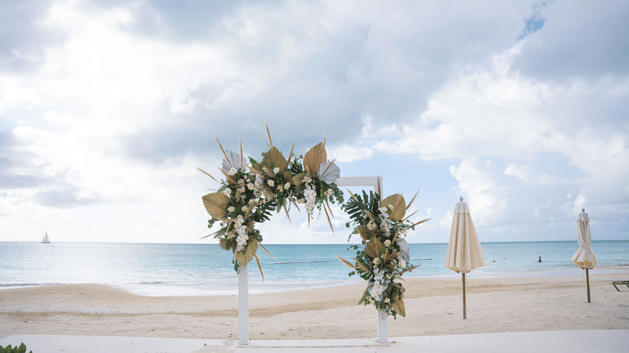 A beachside arch with two closed beach umbrellas, facing the ocean at Tamarind Hills Resort and Villas, Antigua.