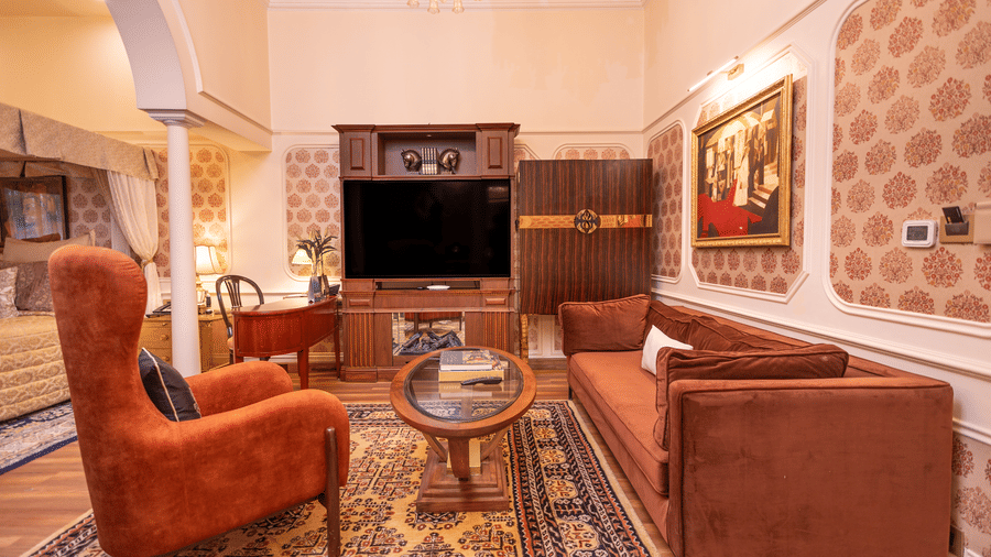 Executive Suite at The Claridges New Delhi, featuring a cosy sofa and corner chair beneath a chandelier