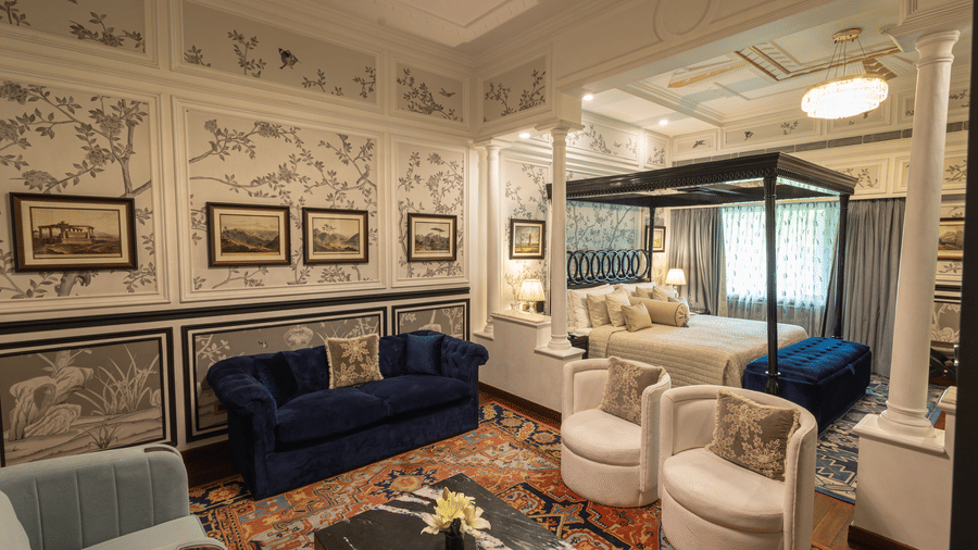 Grand Luxury Room at The Claridges New Delhi, featuring a cosy corner with a plush sofa and a chandelier hanging overhead