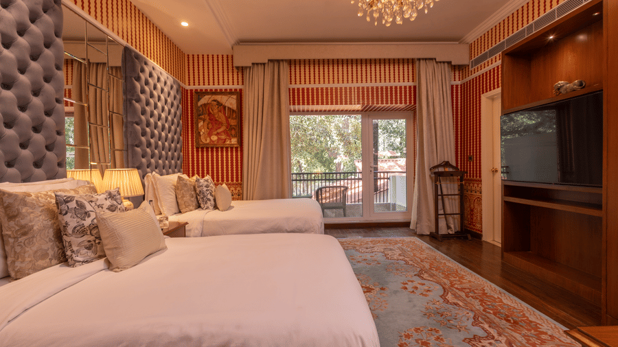 Side view of the spacious Luxury Twin Bed Room with Balcony at The Claridges New Delhi, featuring two separate beds, a stylish candellia hanging