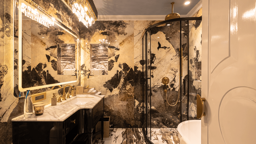 A sophisticated bathroom featuring a white and black gradient marble design and a spacious mirror above the wash basin in the Heritage Parlour Suite - The Claridges New Delhi