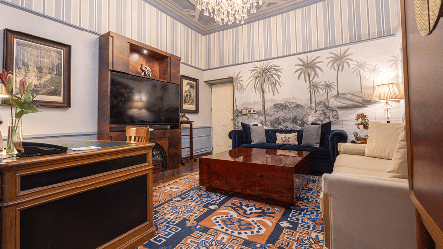 image of the living area from a corner of our heritage parlour suite with a wall mounted television in front of the couch - The Claridges New Delhi