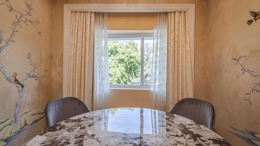 image of a marble dining table with a window at the far end at our lutyens luxury suite - The Claridges New Delhi