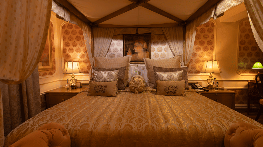 A front view of the Heritage Parlour Suite bed, adorned with a Mughal style painting elegantly positioned on the wall behind the headboard - The Claridges New Delhi