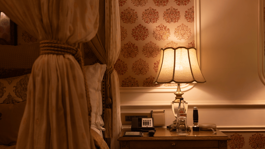 a close up shot of the table lamp besides the plush bedding at the bedroom of our heritage parlour suite - The Claridges New Delhi
