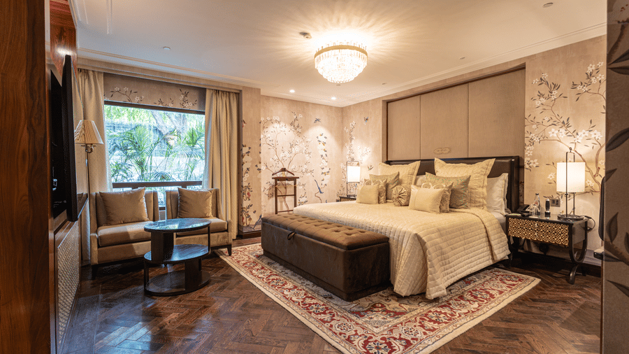 image of the bedroom of the cabana room featuring a modern interior with grey themed colour tone - Image of the Cabana Room featuring two single-seater couches and a wall-mounted television - The Claridges New Delhi
