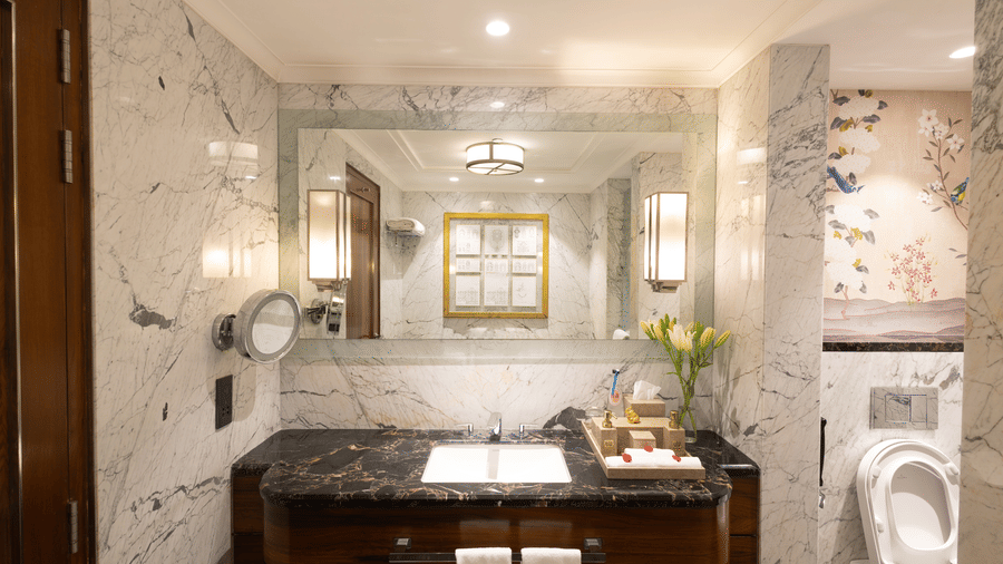 image of an illusive vanity area with a wide mirror above it at our cabana room - Image of the Cabana Room featuring two single-seater couches and a wall-mounted television - The Claridges New Delhi